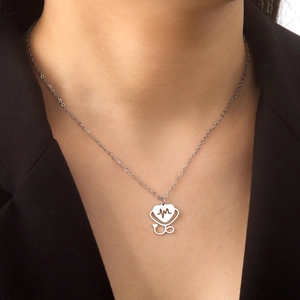 Detailed view of silver heart stethoscope necklace with EKG pulse line on dark blazer