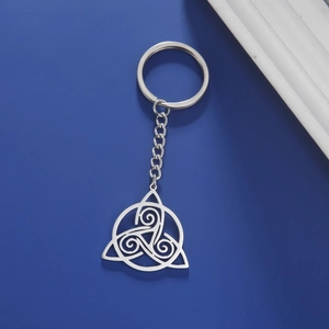 Detailed view of silver Celtic knot pendant keychain on a deep blue textured background