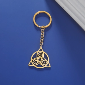 Detail of golden Celtic Triquetra knot keychain with spiral design on blue background