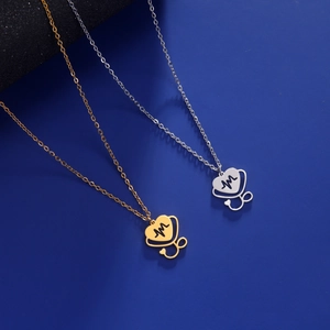 Detail of gold and silver heart stethoscope necklaces with EKG design on blue paper