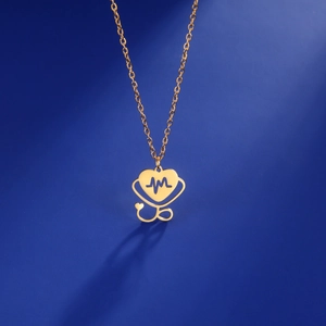 Macro shot of gold stainless steel heart stethoscope pendant on deep blue background
