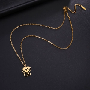 Detail showing a gold heart-shaped stethoscope pendant with EKG line on a black background