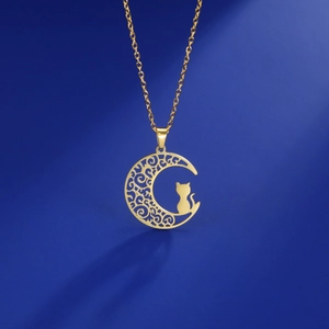 Detailed view of a golden moon and cat silhouette pendant necklace on blue background