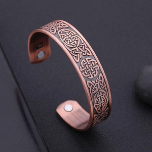 Copper tone magnetic health bracelet with Celtic knot relief and open cuff design