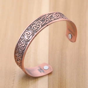 Macro view of vintage copper magnetic therapy cuff with intricate Celtic knot patterns