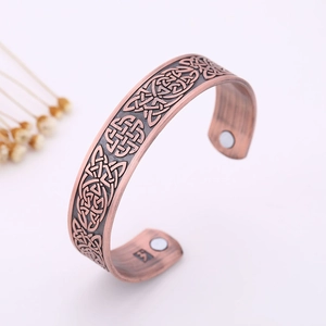 Macro shot of antique red bronze cuff with Celtic knot pattern and magnetic therapy stones