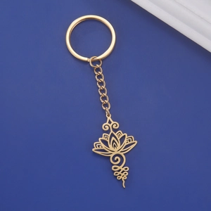Vue détaillée du pendentif lotus unalome en acier doré sur porte-clés avec fond bleu foncé