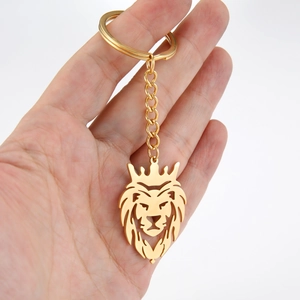 Porte-clés tête de lion doré avec couronne et chaîne courte tenu en main sur fond blanc