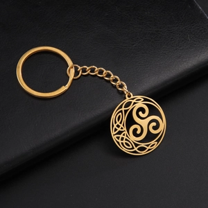 Detail of golden stainless steel Celtic triskelion knot keychain on black leather