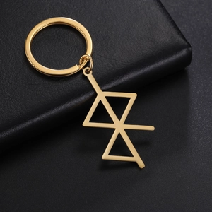 Close-up of geometric gold stainless steel keychain on black leather background texture