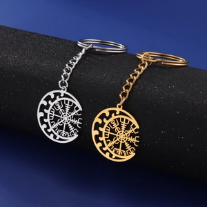 Detail of gold and silver Viking Vegvisir compass keychains on a textured display stand