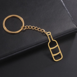 Close-up of golden hollowed wine bottle pendant keychain on black leather texture