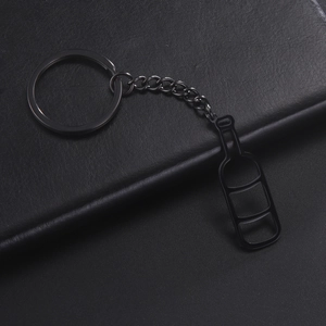 Close-up of a minimalist black stainless steel wine bottle keychain on leather background