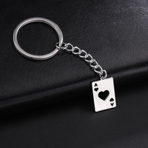 Detail of silver Ace of Hearts hollow pendant on stainless steel keychain with leather background