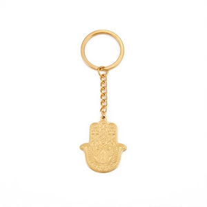 Porte-clés main de Hamsa dorée avec motifs floraux découpés sur fond blanc neutre