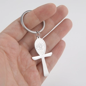 Polished stainless steel Ankh cross keychain with lotus engraving held by a person