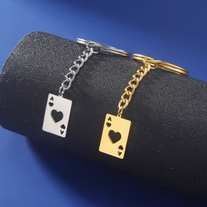 Close-up of polished gold and silver Ace of Hearts playing card pendants on keychains