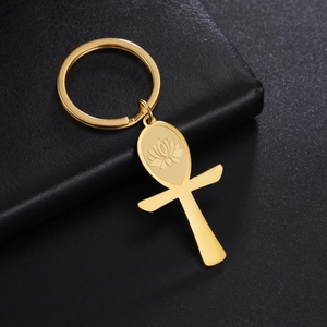 Macro shot of golden Ankh keychain with lotus engraving on black leather surface