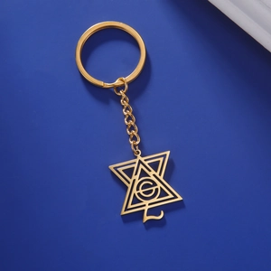 Détail d'un porte-clés doré avec pendentif triangle géométrique et lettre G sur bleu