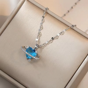 Collier planète cœur bleu avec chaîne argentée et cristaux sur boîte à bijoux en velours