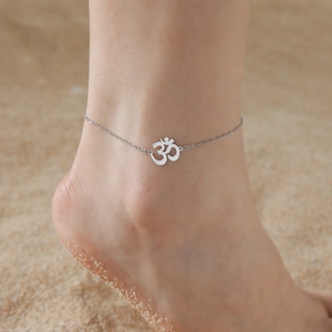 Silver stainless steel double-layered Om charm anklet worn on a sandy beach
