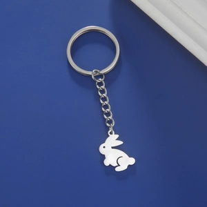 Close-up of a silver stainless steel rabbit pendant keychain on a blue background