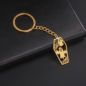 Golden coffin keychain featuring ghosts and cobweb detail on black leather background