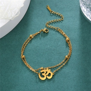 Macro view of gold stainless steel double-layer anklet with Om charm and tiny metal beads