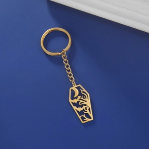 Detalle macro del llavero de ataúd gótico dorado con luna, murciélago y diseño de árbol