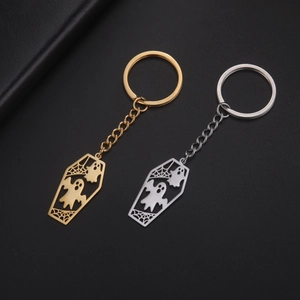 Detail of gold and silver coffin-shaped ghost keychains with intricate hollow spider webs