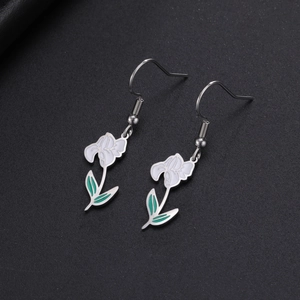 Détail de boucles d'oreilles fleurs en émail blanc et feuilles vertes en métal