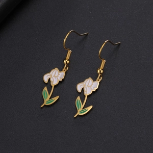 Détail de boucles d'oreilles fleur avec pétales en émail blanc et crochets dorés