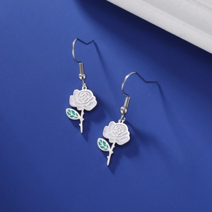 Détail de boucles d'oreilles roses avec pétales en émail blanc et accents de feuilles