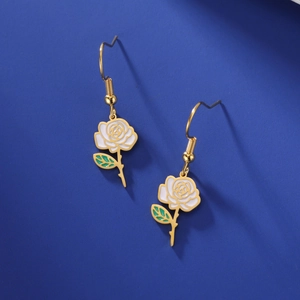 Gros plan de boucles d'oreilles rose en or avec émail blanc et feuilles vertes sur bleu