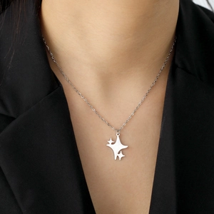 Detailopname van de vierpuntige ster hanger ketting gedragen op een zwart pak