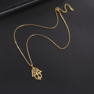 Detailed shot of golden Hamsa hand pendant with tree of life design on black background