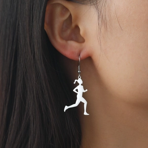 Detail shot of white running girl silhouette drop earrings on a model's ear