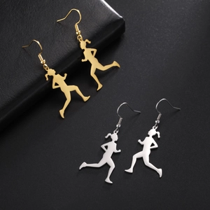 Detailed view of gold and silver running girl dangle earrings on black leather surface