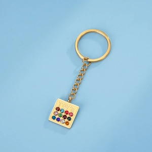 Macro view of golden Hoshen keychain with 12 colorful gemstones and Hebrew engraving