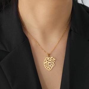 Golden hollow anatomical heart pendant necklace in stainless steel worn on a black suit