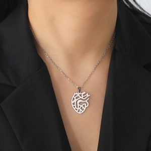 Detail of silver anatomical heart pendant necklace on model wearing black suit jacket
