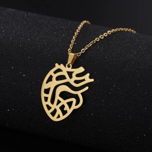 Detailed macro view of gold anatomical heart pendant necklace on dark textured surface