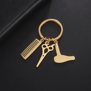 Golden hairdresser keychain with comb, scissors, and hairdryer charms on black leather