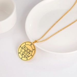 Nahaufnahme der goldenen Edelstahl-Rundanhänger mit HAGENTI-Gravur und geometrischem Muster
