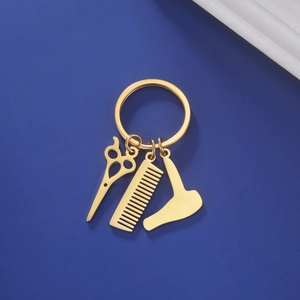 Detailed view of hair salon tool keychains with golden comb, scissors, and blow dryer charm