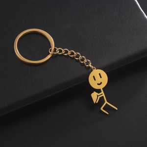 Detail van een gouden stickman sleutelhanger met hart op een zwarte achtergrond