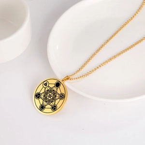 Macro d'un pendentif rond doré en acier inoxydable avec motif de géométrie Metatron