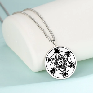 Détail macro du pendentif rond argenté avec géométrie du cube de Métatron gravée