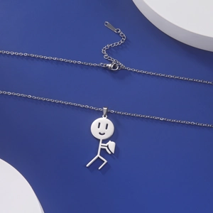 Dettaglio della collana con ciondolo a omino e cuore su uno sfondo blu intenso moderno
