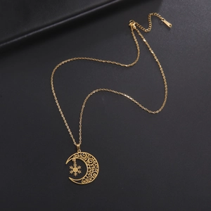 Close-up of golden moon and snowflake pendant with intricate cutout patterns on black background